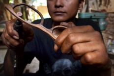 A worker makes a lens hood on a timber frame at a home workshop in Bandungrejo, Malang, East Java, on Aug. 15. JP/Aman Rochman