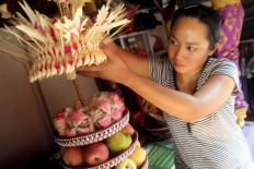 A woman prepares an offering containing fruit and snacks. The offering will be taken to the temple as part of the prayers’ procession in celebrating Galungan. JP/Zul Trio Anggono