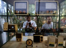 Visitors observe locally made wooden radios in a booth. JP/Ganug Nugroho Adi