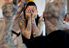 In this picture taken on Sunday, Oct. 16, 2016, a a woman covers her face during the International Tattoo Convention Bucharest 2016 in Bucharest, Romania. More than 100 tattoo and piercing artists brought their skills and art to a three-day convention in the Romanian capital. AP Photo/Vadim Ghirda
