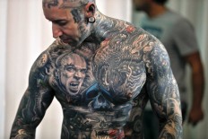 In this picture taken on Sunday, Oct. 16, 2016, Yall Quinones, from Puerto Rico, shows off his tattoos during the International Tattoo Convention Bucharest 2016 in Bucharest, Romania. More than 100 tattoo and piercing artists brought their skills and art to a three-day convention in the Romanian capital. AP Photo/Vadim Ghirda