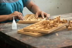 A craftsperson sands a toy puzzle made from mahogany. JP/Aditya Sagita