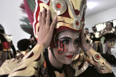 A Topeng Ireng dancer from Boyolali, Central Java, puts on her headdress before a
performance at the 2016 Indonesian Umbrella Festival at Balekambang Park, Surakarta, Central Java. JP / Kus Hendratmo