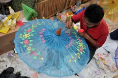 A man paints a name on an umbrella during the 2016 Indonesian Umbrella Festival. Umbrellas decorated with names, produced by artisans from Juwiring, Klaten,
attracted visitors at the festival. JP / Kus Hendratmo