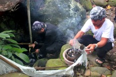 Two community leaders, locally known as kokolot, take water from a spring in the Sindangbarang traditional kampung, Tamansari district, Bogor, during the Seren Taun Guru Bumi ceremony. JP/Theresia Sufa
