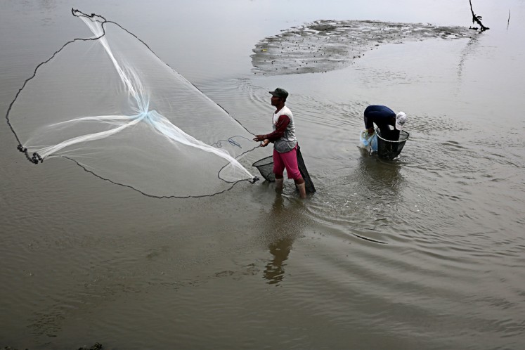 A traditional fisherman nets shrimps and fish in shallow waters along Banda Aceh Beach in Aceh on Oct.29. 