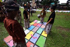 Four children play a giant version of the snakes and ladders board game during the parade organized by Sanata Dharma University. JP/ Aditya Sagita