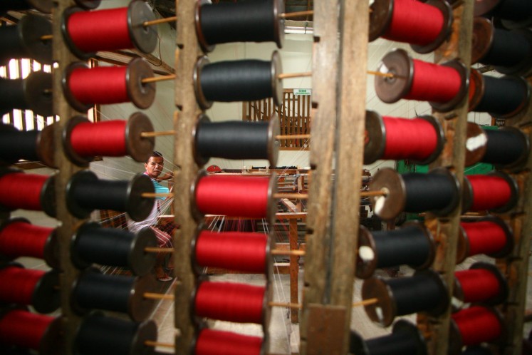 A man arranges yarn by color to weave them into lurik motifs.