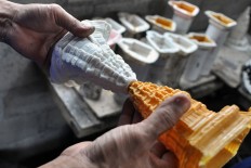 A man peels off a white rubber mold from a resin figurine. Latex rubber is used to make detailed figurines. JP/Magnus Kushendratmo