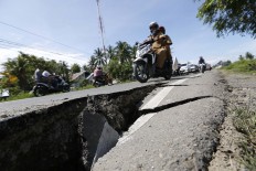 Motorcycles pass a damaged road caused by a strong earthquake in Pidie Jaya regency, Aceh. JP/ Hotli Simanjuntak