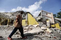  A man walks past a collapsed mosque in Pidie Jaya on Dec. 7. Several regencies in Aceh were hit by the quake but Pidie Jaya experienced the heaviest impact. JP/ Hotli Simanjuntak