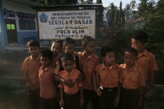 Students of Pulo Ulim elementary school in Pidie Jaya regency, Aceh, stand in front of their school’s sign on their first day back in class after the Dec. 7 earthquake. JP/ Dhoni Setiawan