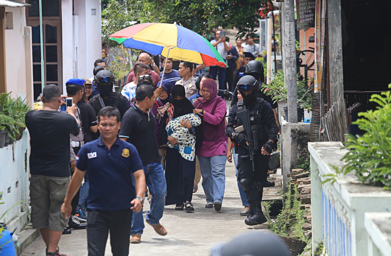 Tight escort – Personnel of the National Police’s Densus 88 counterterrorism squad pick up Rinda (center), 24, the wife of terrorist suspect Nur Solihin from their house in Kampung Griyan, Laweyan, Surakarta, Central Java, on Sunday. She was taken into custody following the arrest of Nur Solihin in Jakarta.