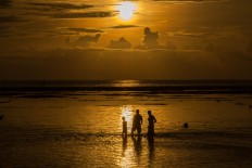 Three men watch the first sunrise of 2017 paint the world a glorious yellow at Sanur Beach in Bali on Sunday. JP/ Agung Parameswara