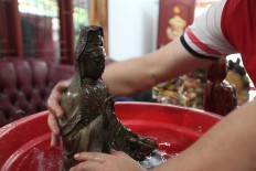 Holy statue: The proprietor of Bio Dhama Kencana Temple, Setia Darma, washes a statue in a ritual called the kim sin shower in Kampung Melayu Barat, Tangerang, Banten. JP/ Donny Fernando