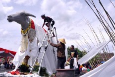 A man climbs on top of the buffalo to unveil the white cloth covering the statue before the ceremony of the Kebo Ketan slaughter in Sekarputih village, Widodaren, Ngawi, East Java last month. JP/ Magnus Hendratmo