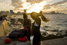 In this Jan. 30, 2017 photo, boxers Idamerys Moreno, left, and Legnis Cala, get ready for a photo session on Havana's Malecon, in Cuba. Moreno trains at least two hours a day after she gets off work, completing a routine that includes running several miles, lifting weights, hitting a punching bag and sparring with both women and men. AP/Ramon Espinosa