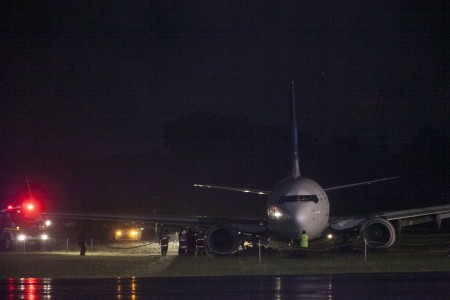 Workers evacuate a Garunda plane, a Boeing 737-800 NG, which slipped on the runway and overshot a lane on Wednesday night. It carried 123 passengers, who were unharmed.