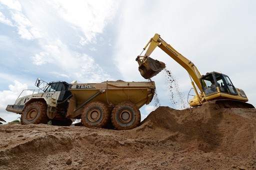 A backhoe loads soil containing tin-bearing sand onto a truck at a mine belonging to metal producer PT Timah in Sungailiat on Bangka Island in Bangka-Belitung Islands province.