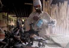 A worker sprays a clear coating onto a classic airplane miniature. JP/ Ganug Nugroho Adi