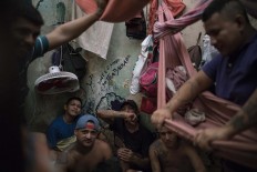 In this Feb. 6, 2017 photo, detainees sit inside an overcrowded cell at a police station near Manaus, Brazil. The walls are filled with infiltrations of moisture, the poor construction of the roof let almost no light shine inside and inmates put hammocks one on the top of the other, while one prisoner slept in the open bathroom. AP Photo/Felipe Dana
