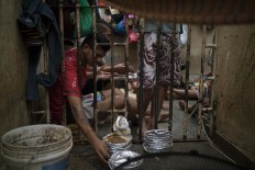In this Feb. 6, 2017 photo, an inmate reaches for a plate of food during lunchtime inside an overcrowded cell at a police station near Manaus, Brazil. The business strategy of Brazilian crime gangs is to dominate overcrowded prisons, then control the streets. AP Photo/Felipe Dana