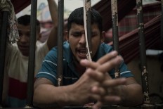 In this Feb. 6, 2017 photo, a detainee prays inside an overcrowded cell at a police station near Manaus, Brazil. All 24 detainees being held in this space made for eight said they hoped to avoid being transferred to a bigger prison under gang rule. AP Photo/Felipe Dana