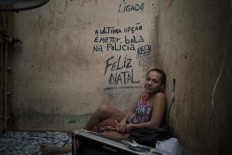In this Feb. 6, 2017 photo, female prisoner Regiane sits on her bed inside a corridor between two cells crowded with men at a police station near Manaus, Brazil. The message on the wall reads in Portuguese: "The last option is to put a bullet in the police. Merry Christmas." AP Photo/Felipe Dana