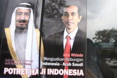 A poster of King Salman bin Abdulaziz Al Saud and President Joko "Jokowi" Widodo hangs in a window at Halim Perdanakusuma Airport. JP/Dhoni Setiawan