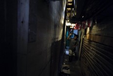 In dim light: Pio carries a water bottle to a customer's home through a narrow alley. JP/ Jerry Adiguna
