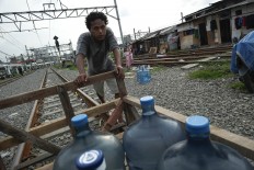 Heavy load: Pio pushes his cart of water bottles on a railway line in Kampung Muka, Ancol, North Jakarta. He has to memorize the train schedules to allow him to use his cart on the track safely. JP/ Jerry Adiguna