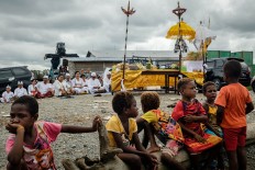 Balinese Hindus pray for the Melasti ritual while Kamoro children sit and watch quietly at the Mimika coast. JP/Vembri Waluyas
