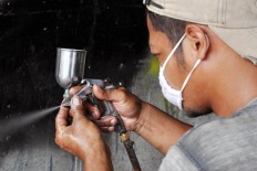 A worker sets the air pressure of a paint sprayer. JP/Magnus Koeshendratmo