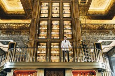 Jason Williams, the bar's gin master, is dwarfed by the three-story gin tower.