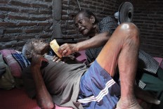 Sugiyem gives a rice cracker to his father. Rice crackers were Mbah Jo Gotho's favorite snack. JP/Magnus Hendratmo