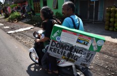 A volunteer rides a motorcycle to help Samsudin on his storytelling tour in Malang, East Java, on April 4. JP/Aman Rochman