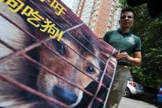 Humane Society International activist Peter Li holds a protest banner near the Yulin government office in Beijing on June 10, 2016. A group of Chinese and international animal activists presented a petition signed by 11 million people calling on authorities to end the annual Yulin dog meat festival. The activists claim thousands of dogs, many of the them stolen from pet owners, are slaughtered each year for the festival, which begins in the southern city of Yulin on June 21.