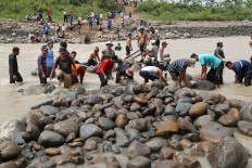 Hard work: Villagers collect rocks from the river to build pillars for the emergency semi-permanent bridge. JP/ PJ Leo