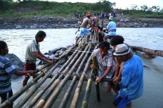 Coming together: Villagers from both sides of the river try best to build an emergency semi-permanent bridge using bamboo. JP/ PJ Leo