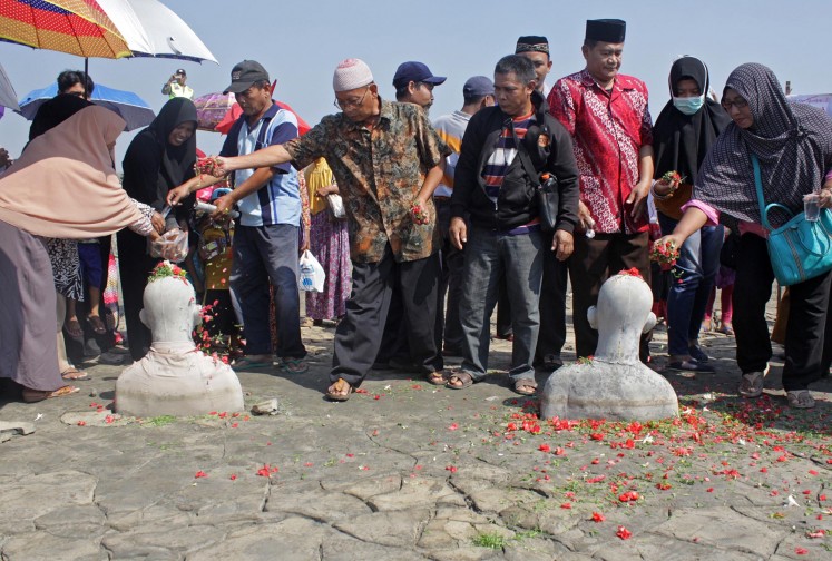 People impacted by the Lapindo mudflow disaster scatter flowers during the commemoration of the eleventh anniversary of the event in Porong, Sidoarjo, East Java, on Wednesday. Eleven years after the mudflow, there are still 244 claims that have not been completed with payments worth Rp 54.3 billion (US$3.3 million) and 19 follow-up claims belonging to residents with a value of Rp 9.8 billion as well as compensation for 30 companies with a claim value of Rp 701 billion. 