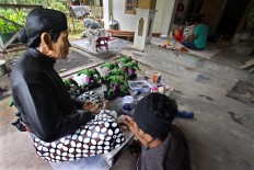 A man paints batik fabric details on a Yogyakarta royal servant sculpture at Patuk, Gunungkidul, Yogyakarta, on Feb. 21. JP/Aditya Sagita