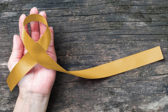 A stock illustration features a gold ribbon, which stands for childhood cancer awareness.