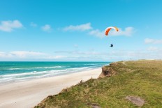 An illustration of paragliding at a deserted beach.