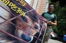 Humane Society International activist Peter Li holds a protest banner near the Yulin government office in Beijing on June 10, 2016. A group of Chinese and international animal activists presented a petition signed by 11 million people calling on authorities to end the annual Yulin dog meat festival. 