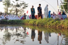 Residents of Nglinggi, Kebonarum, Klaten, Central Java, are reflected in a shallow pool as they prepare for the Ied prayer in a field on Sunday, June 25, 2017. JP/Magnus Hendratmo