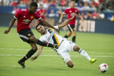 Manchester United's Marcus Rashford kicks the ball past Hugo Arellano of Los Angeles Galaxy during a friendly match in Carson, California.