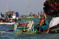 A man throws an offering into the sea after his boat swamps during the Lomban procession in Jepara Bay, Central Java, on July 2. People believe those who grab any items would be blessed. JP/Maksum Nur Fauzan
