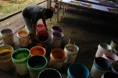 A craftman pours vats of paint in preparation for dyeing beach sarongs. JP/Aman Rochman