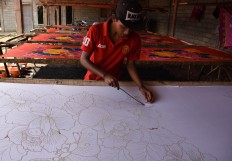 A craftman draws a floral pattern in malam (hot wax) to create a sarong using the wax-resist dyeing technique. JP/Aman Rochman