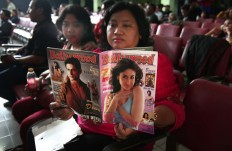 A visitor reads a Bollywood magazine while waiting for the Bollywood festival to start at the Gajayana Playhouse in Malang, East Java, on Sept. 21, 2014. JP/Aman Rochman